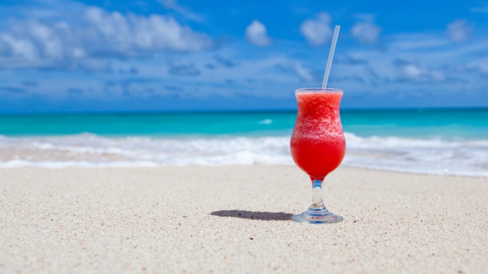 Cocktail on a sandy beach with ocean waves