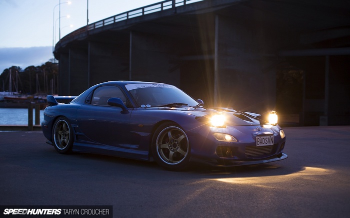 Mazda RX-7 parked under a bridge at dusk