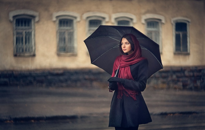 Woman with umbrella in front of building