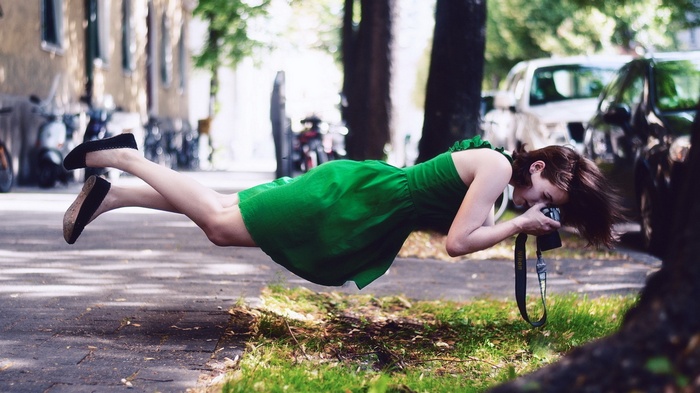 Woman in green dress floating and taking a photo