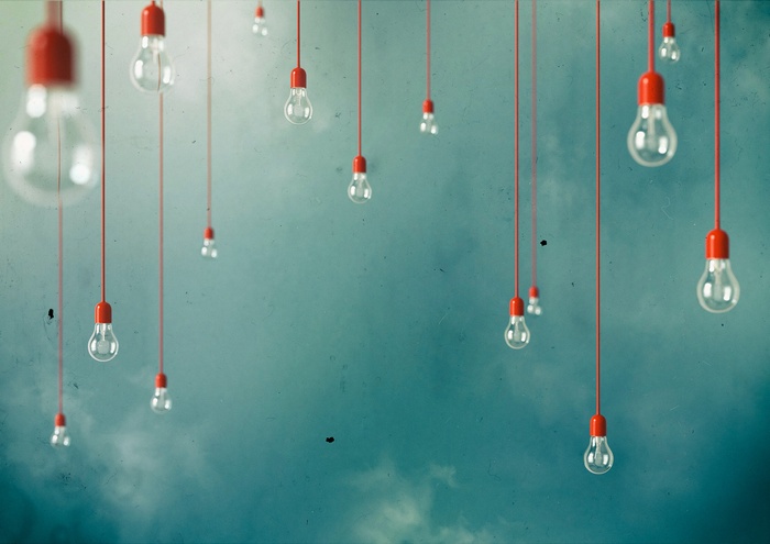 Light bulbs hanging from red cords against cloudy sky