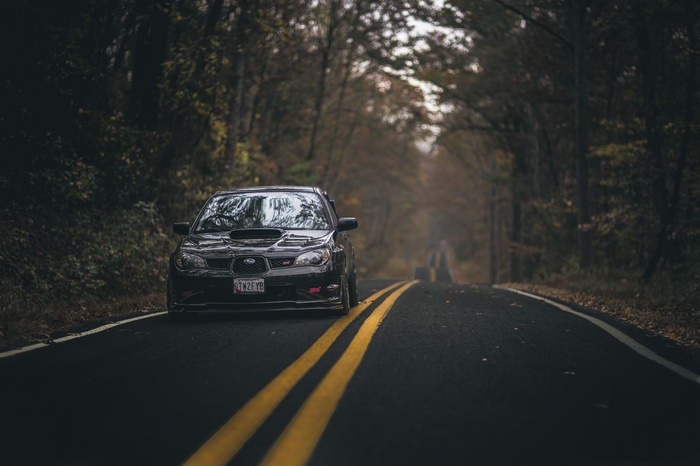Black Subaru WRX STI on a forest road