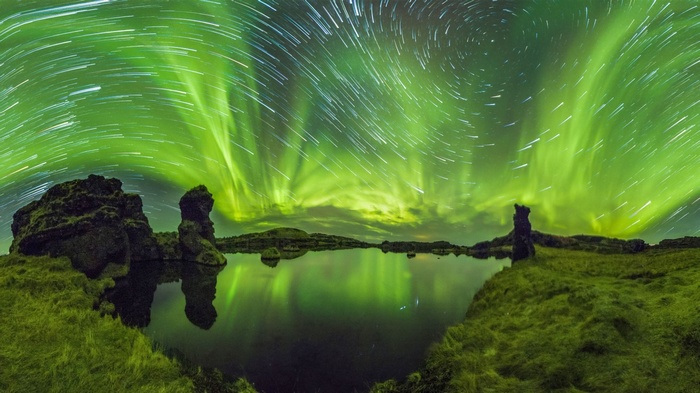 Aurora Borealis over a lake with star trails