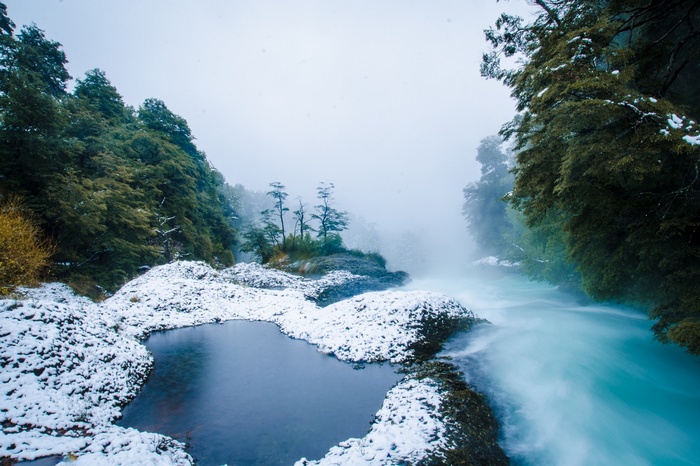 Chilean river and forest with snow and mist