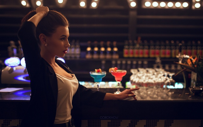 Woman in black jacket and white top at bar