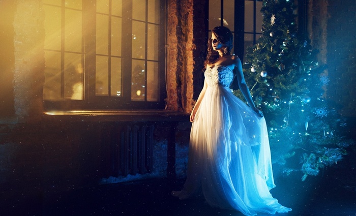 Woman in a white dress by a Christmas tree