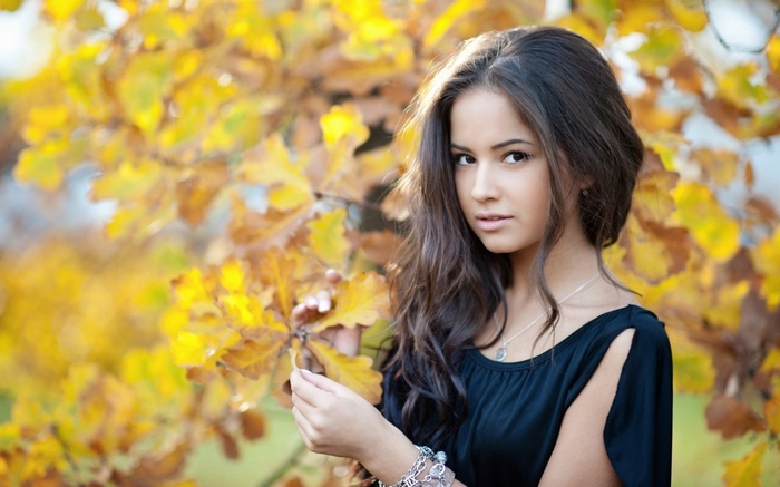 Woman in black dress with autumn leaves
