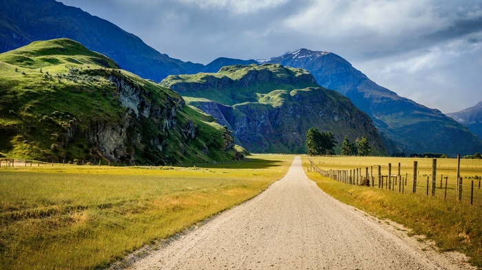 Dirt road through a valley with green mountains