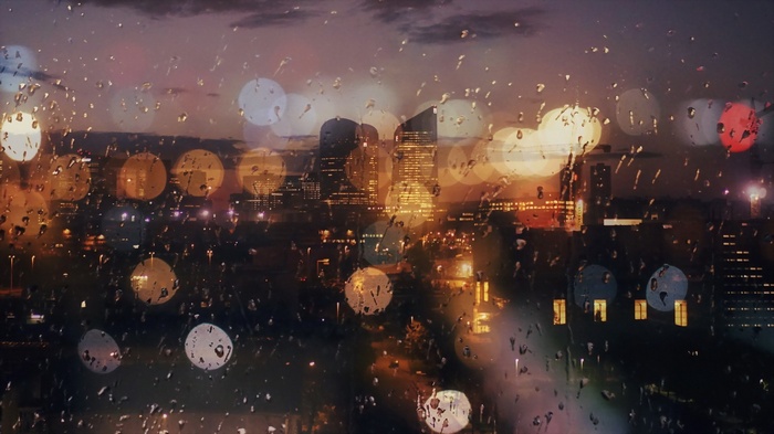 Cityscape at dusk through a rain-streaked window