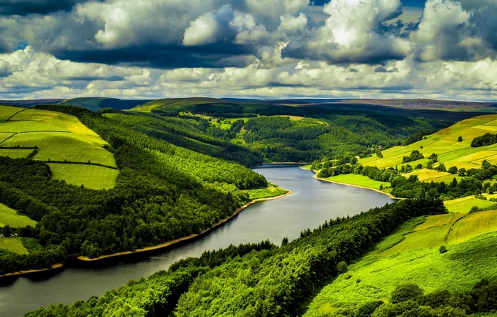 A winding river flows through green hills under a cloudy sky.