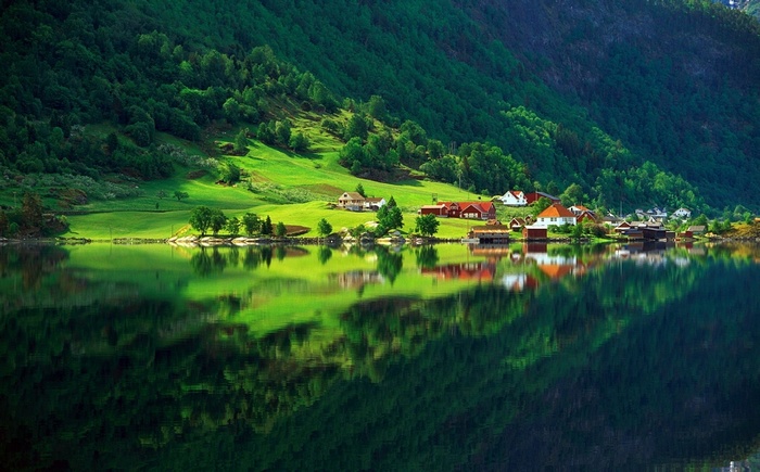 Green hillside village reflected in a calm lake