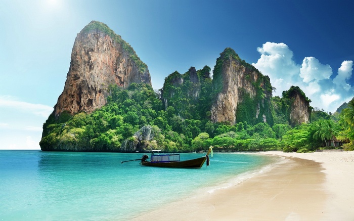 Boat on a tropical beach with limestone cliffs