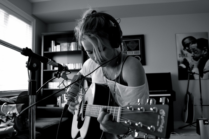 Emily Osment playing guitar with headphones