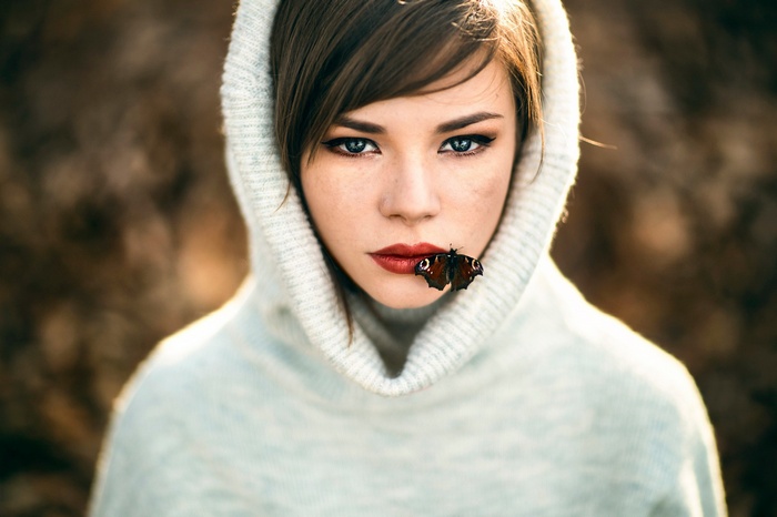 Woman with butterfly on her lips wearing a hood