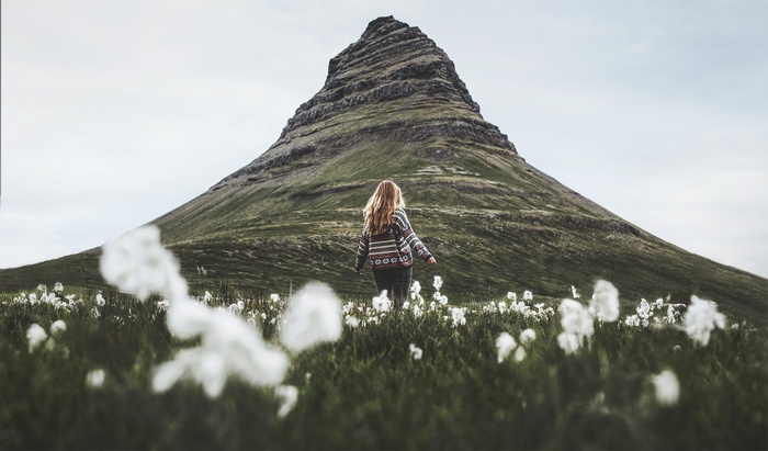 Woman walking in a field with a mountain behind her