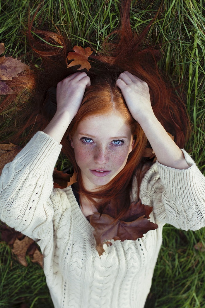 Redhead woman with blue eyes lying in grass