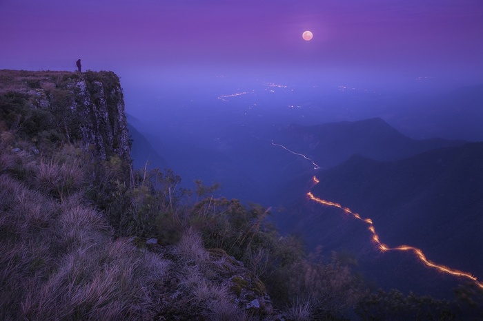 Moonlit cliff overlooking a valley with a winding road in Brazil