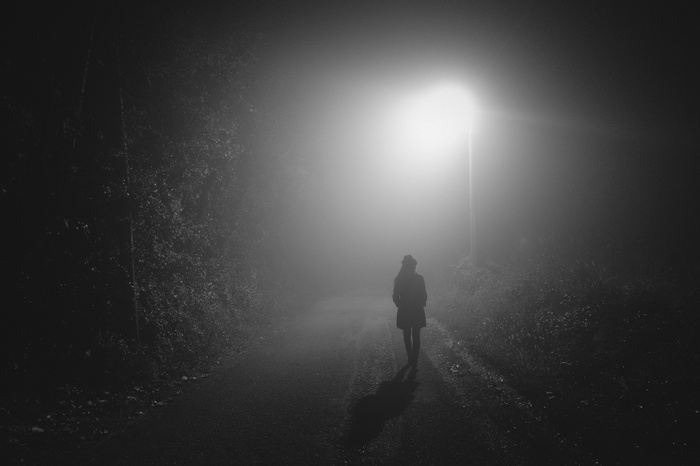 Person walking on a foggy path at night