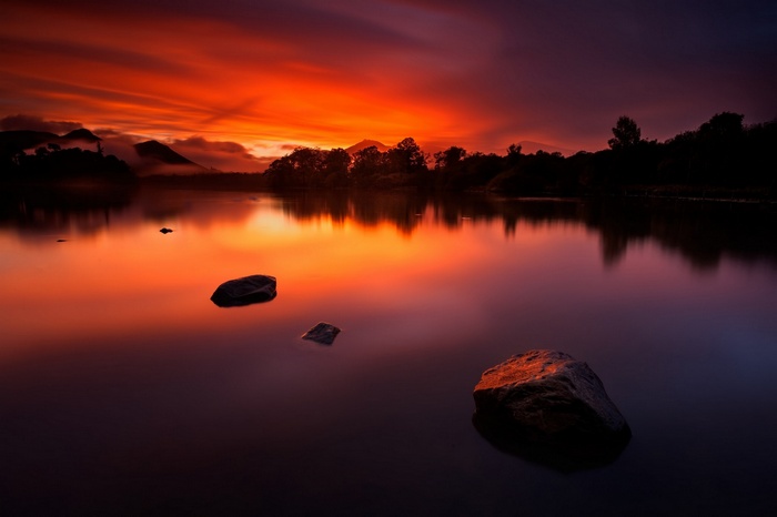 Sunset over a calm lake with rocks