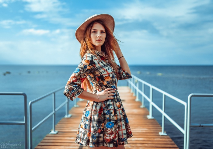 Woman in a colorful dress and hat on a pier
