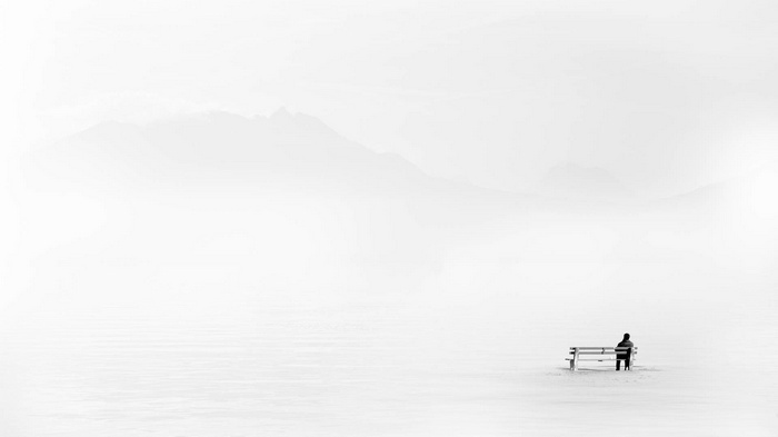 Man sitting on a bench in a snowy landscape with mountains