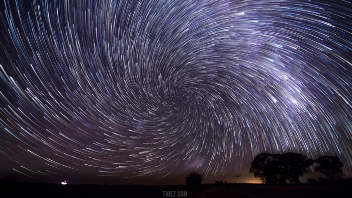 Spiral Star Trails Over Silhouetted Trees