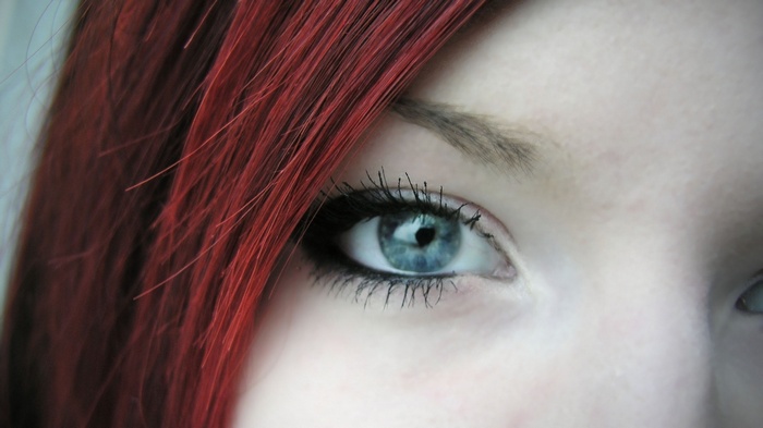 Close-up of a woman's blue eye and red hair