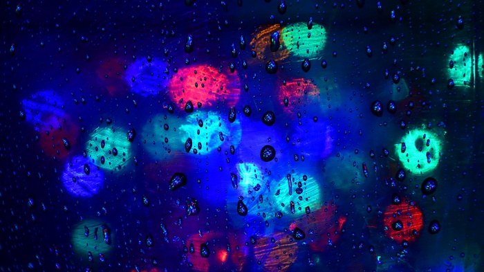 Raindrops on glass with colorful bokeh lights