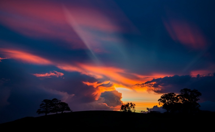 Sunset over a silhouetted landscape with dramatic clouds