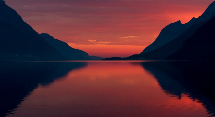 Sunset over a calm lake between mountains