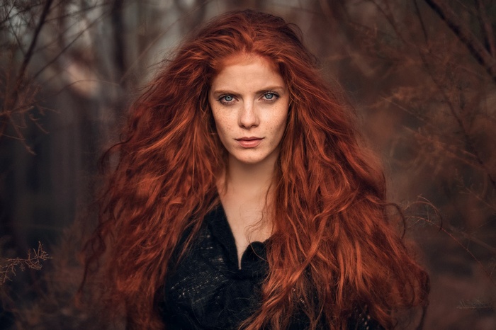 Redhead woman with blue eyes in a forest
