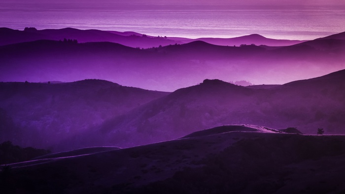 Purple mountains and ocean at sunset