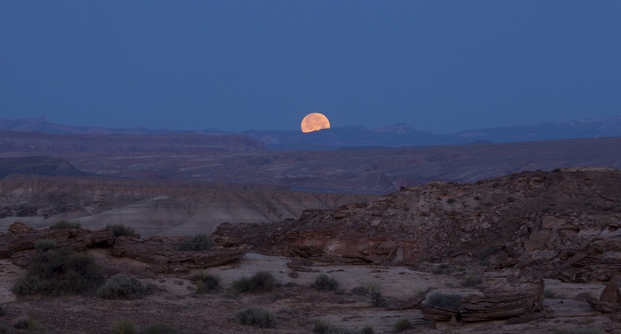 Moon rising over a desert landscape