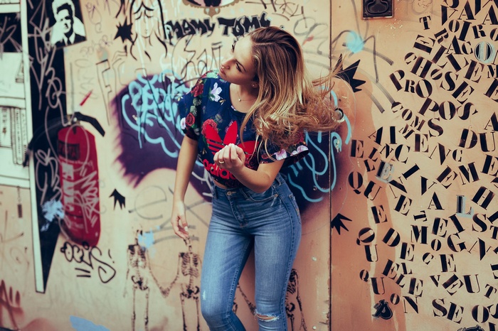 Woman in Adidas crop top and jeans against graffiti wall