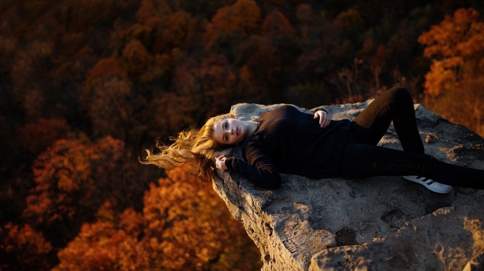 Woman with long blonde hair lying on a rock