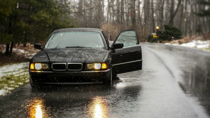 Black BMW 740 parked on a wet road in the rain