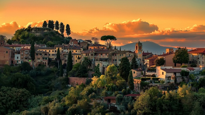Tuscan village at sunset with rolling hills and clouds
