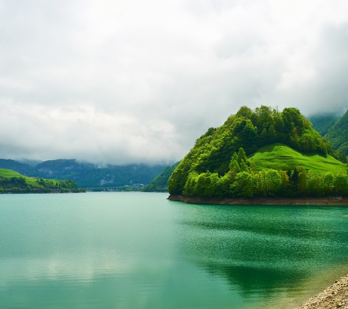 Green island in a turquoise lake with cloudy sky