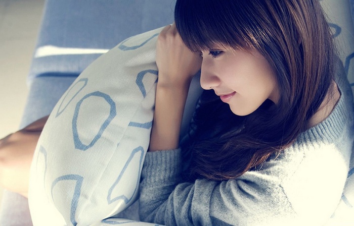 Asian woman holding a pillow on a couch