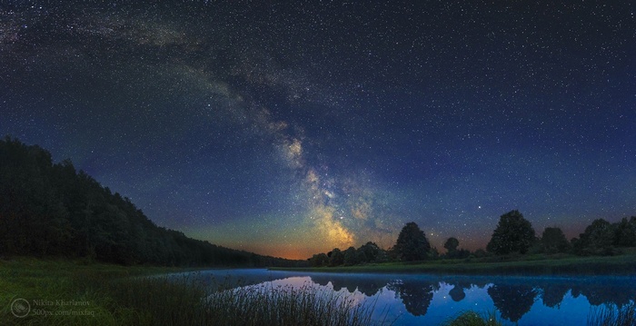 The Milky Way Galaxy over a calm river at night