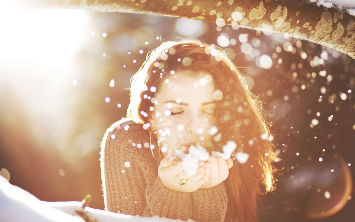Woman blowing snow in winter sunlight