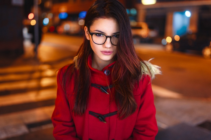 Woman in red coat with glasses at night