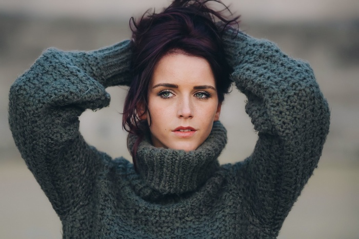 Woman with hands in hair wearing a turtleneck sweater