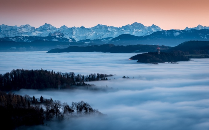 Snowy mountains over a sea of fog in Switzerland