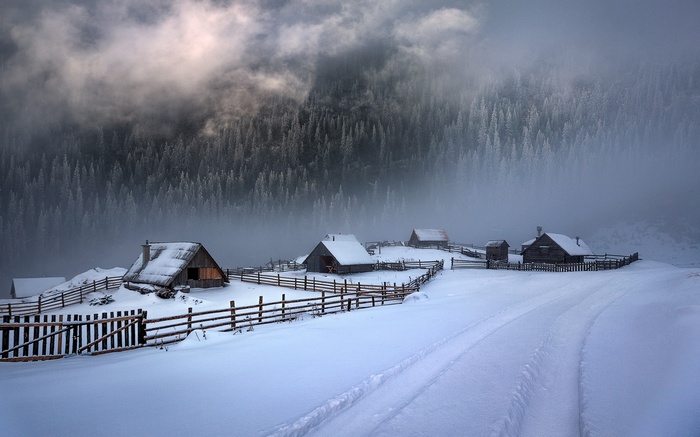 Winter landscape with cabins and misty mountains