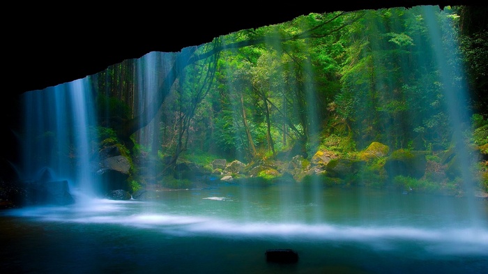 Waterfall cascading into a jungle pool with sunbeams