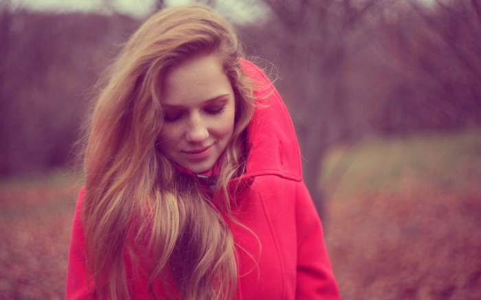 Woman with long blonde hair in a red coat outdoors