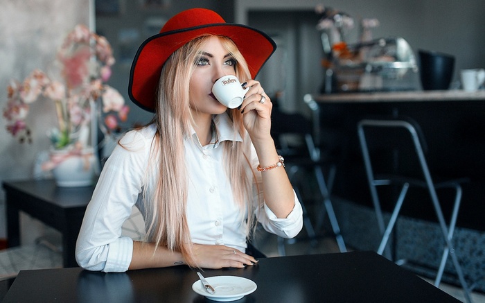 Woman in red hat drinking coffee at a table