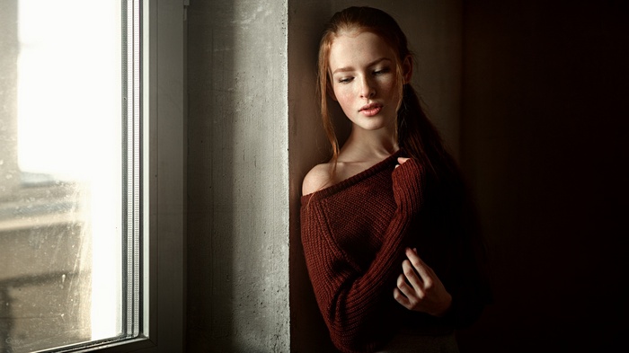 Katya Voronina in a sweater by a window