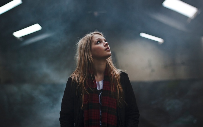 Woman with blonde hair looking up in a smoky room